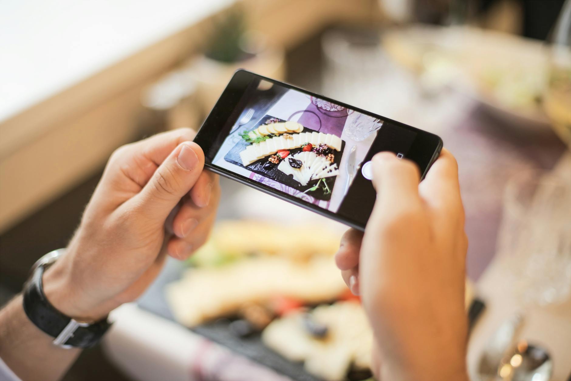 Gastronom fotografiert mit dem Smartphone einen Teller — eigene Fotos lassen das Google-Unternehmensprofil in der Maps-Box auffallen