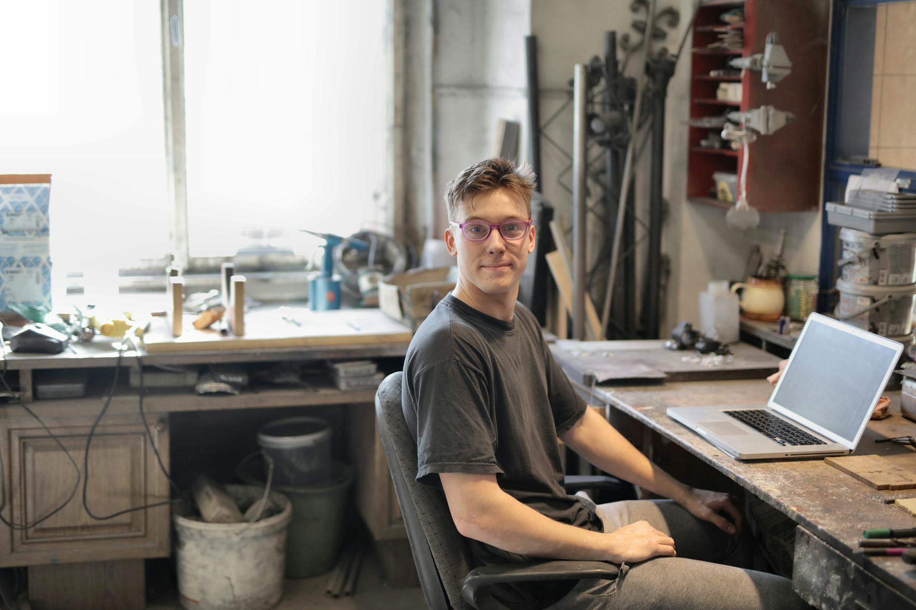 Junger Handwerker am Werkbank plant die eigene Website für Handwerker am Laptop